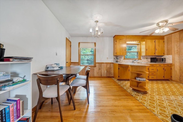 kitchen featuring pendant lighting, a healthy amount of sunlight, light hardwood / wood-style floors, and wood walls