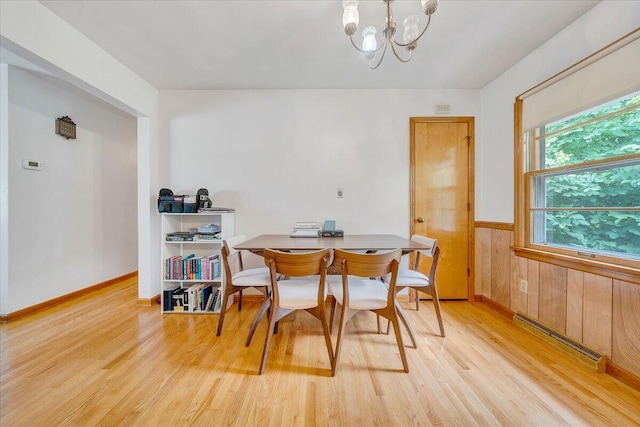 dining area featuring a baseboard heating unit, hardwood / wood-style floors, a notable chandelier, and wood walls