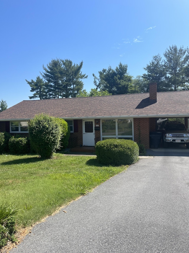 ranch-style home with a carport and a front lawn