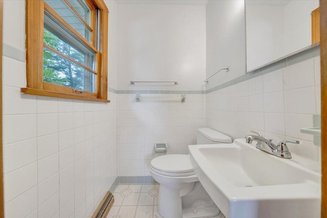 bathroom featuring tile patterned floors, toilet, sink, and tile walls