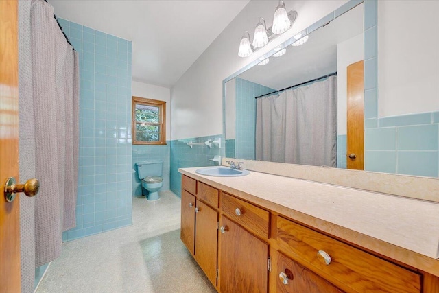 bathroom with walk in shower, vanity, toilet, and tile walls