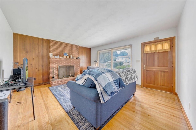 living room featuring hardwood / wood-style flooring, a brick fireplace, and wood walls