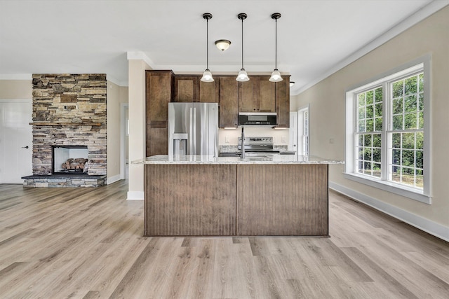 kitchen with light stone countertops, hanging light fixtures, appliances with stainless steel finishes, and ornamental molding