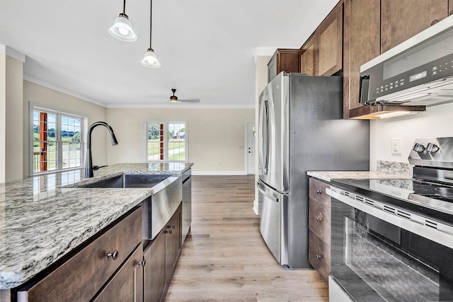 kitchen featuring light hardwood / wood-style floors, crown molding, light stone countertops, and stainless steel appliances