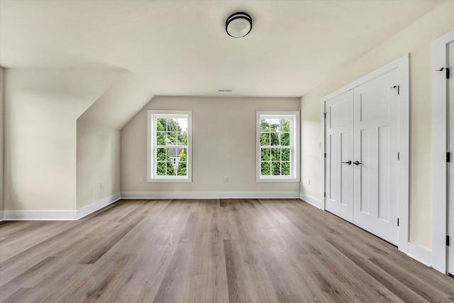 bonus room featuring light wood-type flooring and vaulted ceiling