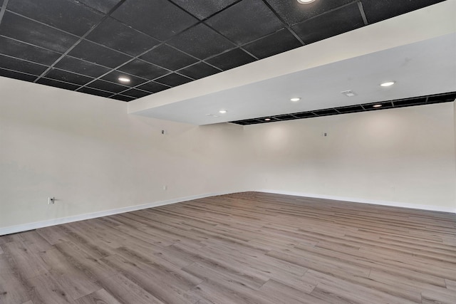 spare room with a paneled ceiling and light wood-type flooring