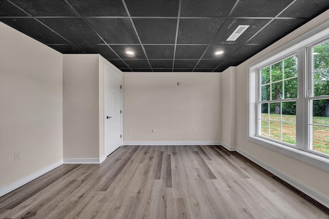 spare room with a drop ceiling and light hardwood / wood-style flooring