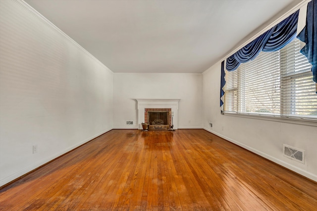 unfurnished living room with crown molding, hardwood / wood-style floors, and a brick fireplace