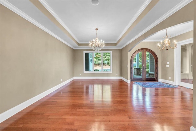 unfurnished dining area with a notable chandelier, wood-type flooring, and french doors