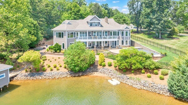 rear view of property with a sunroom, a patio, and a water view