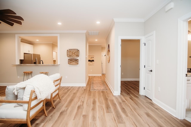 hallway with light hardwood / wood-style flooring and crown molding