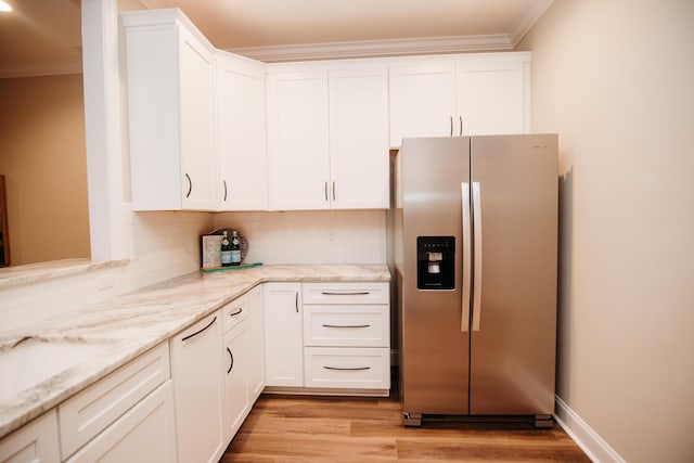 kitchen with backsplash, light stone countertops, white cabinets, and stainless steel refrigerator with ice dispenser