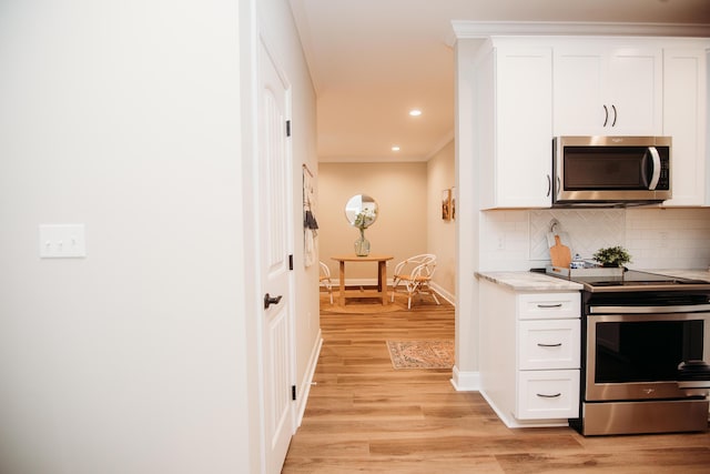 kitchen featuring light stone countertops, appliances with stainless steel finishes, backsplash, ornamental molding, and white cabinets