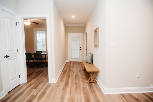 corridor with light wood-type flooring and ornamental molding