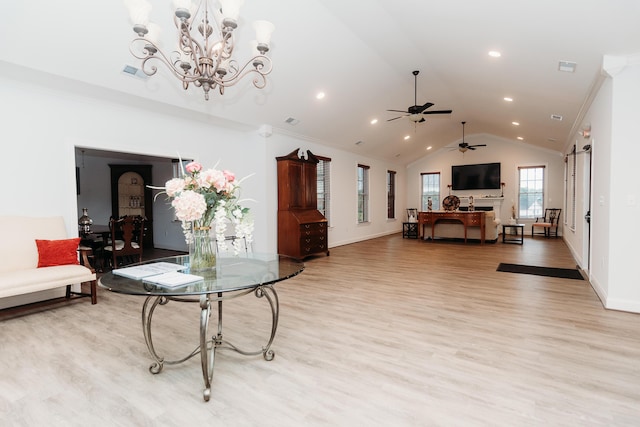 living room with ceiling fan with notable chandelier, light hardwood / wood-style floors, vaulted ceiling, and ornamental molding