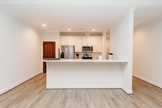 kitchen with appliances with stainless steel finishes, light wood-type flooring, backsplash, ornamental molding, and white cabinetry