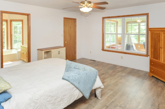 bedroom featuring baseboards, ceiling fan, light wood finished floors, and ensuite bathroom