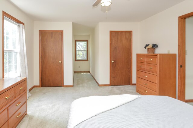 bedroom featuring baseboards, multiple closets, a ceiling fan, and light colored carpet