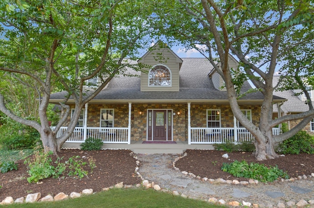 view of front of home featuring stone siding, a shingled roof, and a porch