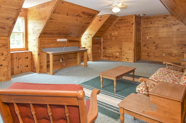 interior space with carpet floors, ceiling fan, wooden walls, and lofted ceiling