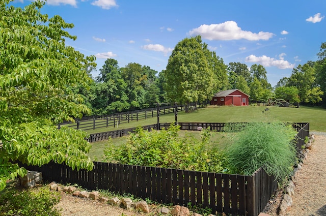 view of yard featuring an outbuilding, a rural view, and fence