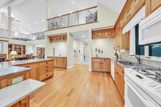 kitchen featuring ceiling fan, sink, white appliances, high vaulted ceiling, and light wood-type flooring