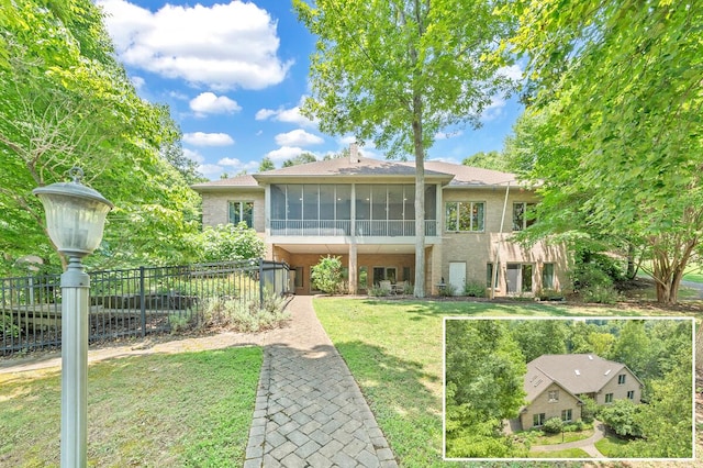 view of front of property featuring fence, a front lawn, and a sunroom