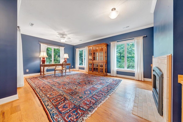 office area with ceiling fan, light hardwood / wood-style floors, ornamental molding, and a wealth of natural light