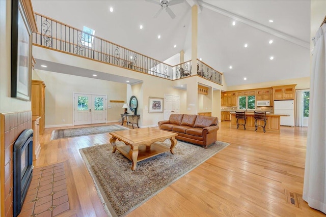 living room with high vaulted ceiling, light hardwood / wood-style flooring, beamed ceiling, and ceiling fan