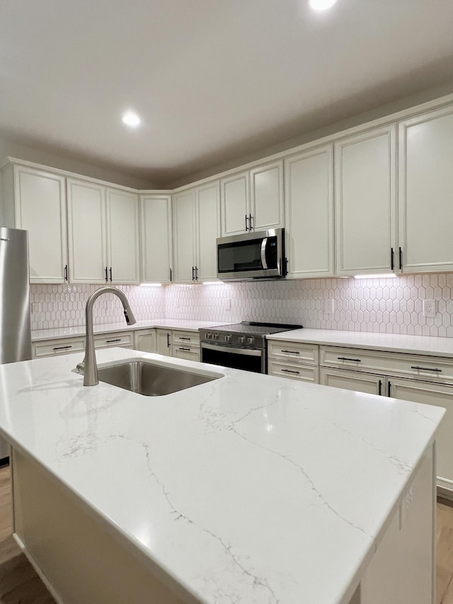 kitchen with stainless steel appliances, light stone counters, light hardwood / wood-style floors, and sink