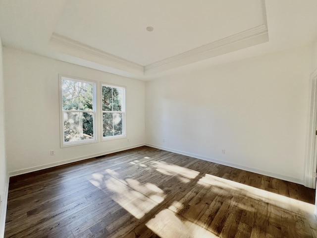 unfurnished room featuring a raised ceiling, crown molding, and dark hardwood / wood-style flooring