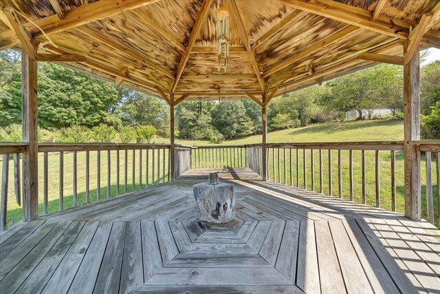 wooden terrace featuring a lawn and a gazebo