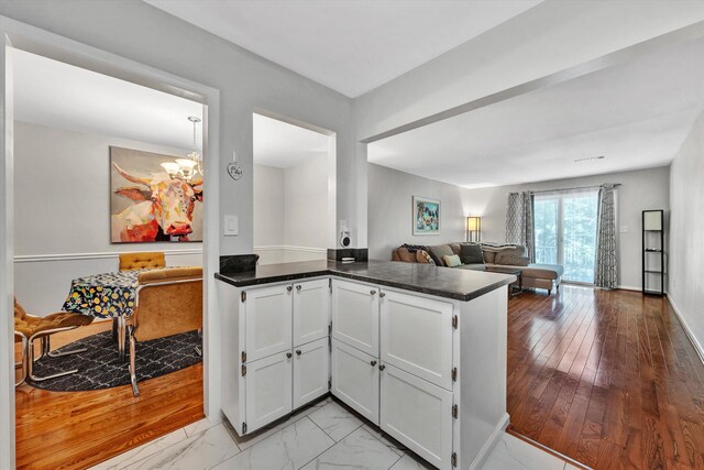 kitchen with white cabinets, light wood-type flooring, and kitchen peninsula