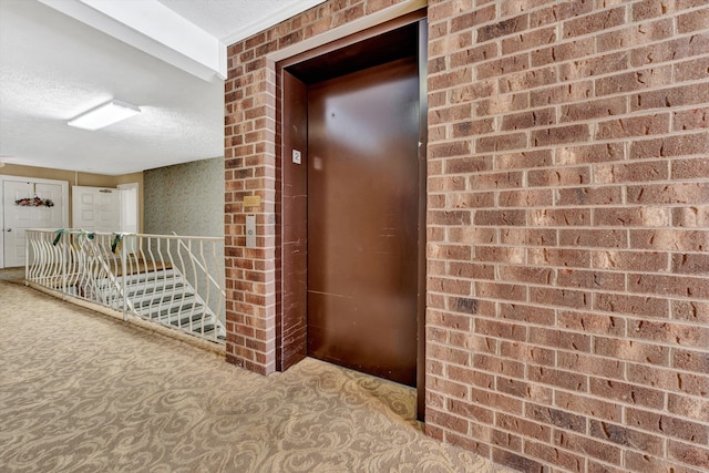 hallway with elevator, carpet, and a textured ceiling