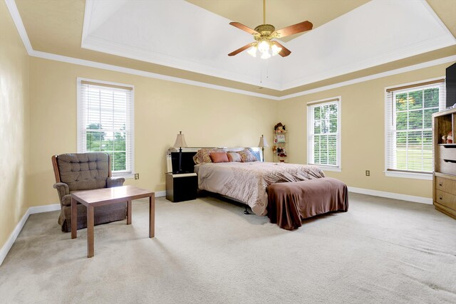 bedroom featuring ceiling fan, light carpet, a tray ceiling, and ornamental molding