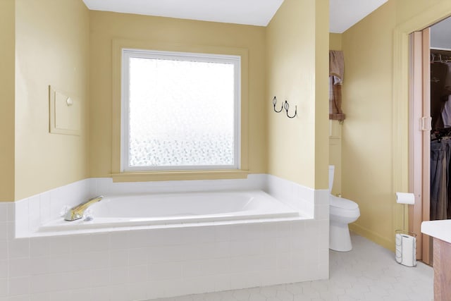 bathroom featuring tiled bath, toilet, and tile patterned flooring