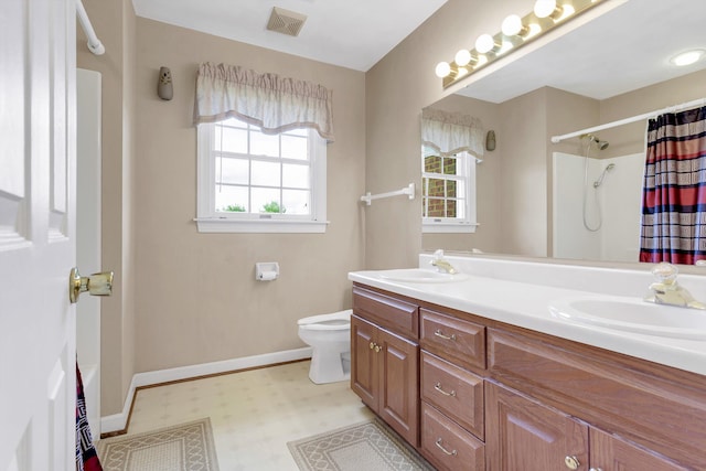 bathroom with tile patterned floors, double sink vanity, and toilet