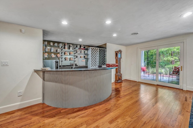 bar with light hardwood / wood-style floors and stainless steel refrigerator