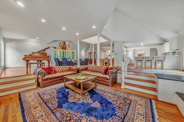 living room featuring high vaulted ceiling, light hardwood / wood-style flooring, and a notable chandelier