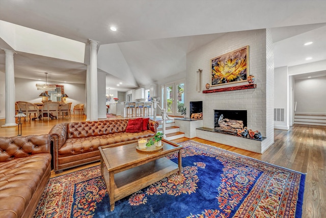 living room with hardwood / wood-style floors, lofted ceiling, and a brick fireplace