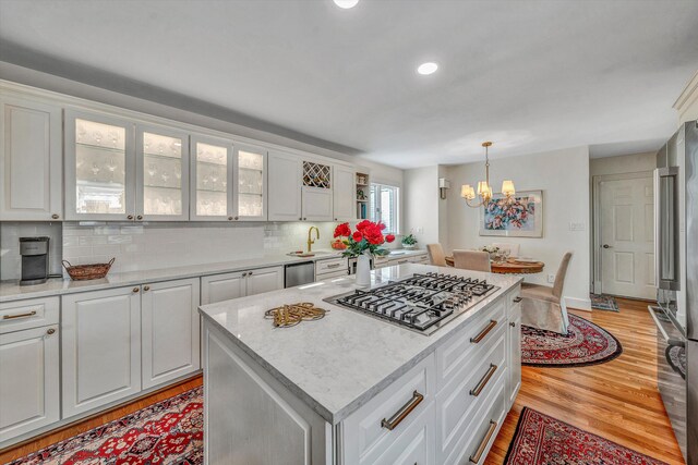 kitchen featuring hanging light fixtures, light hardwood / wood-style flooring, a kitchen island, white cabinetry, and stainless steel appliances