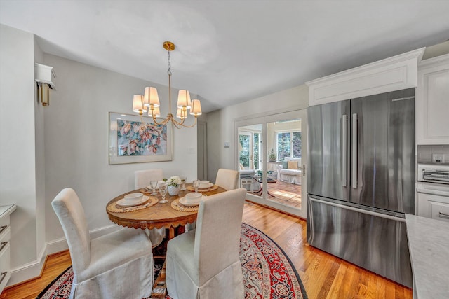 dining room with light hardwood / wood-style floors and an inviting chandelier