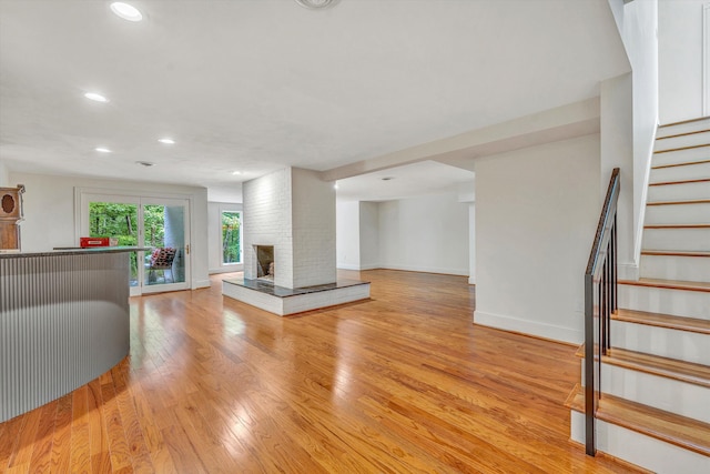 unfurnished living room featuring light hardwood / wood-style floors and a brick fireplace