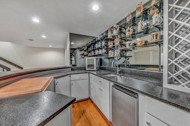 kitchen featuring kitchen peninsula, light wood-type flooring, white cabinetry, and sink