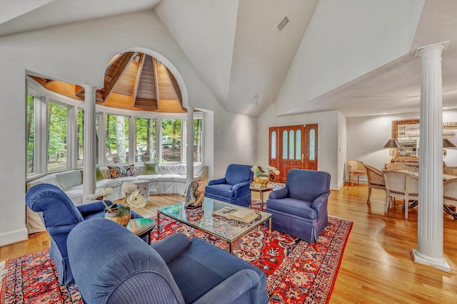 living room with light wood-type flooring, high vaulted ceiling, and decorative columns