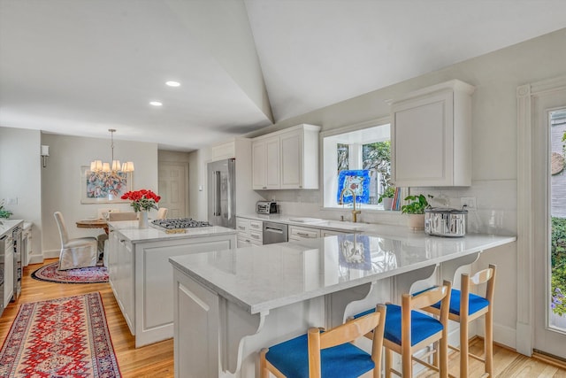 kitchen with pendant lighting, light hardwood / wood-style floors, white cabinetry, and stainless steel appliances