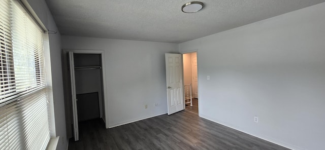 unfurnished bedroom with dark wood-type flooring, a closet, and a textured ceiling