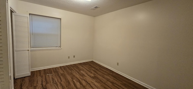 unfurnished room with dark hardwood / wood-style flooring and a textured ceiling