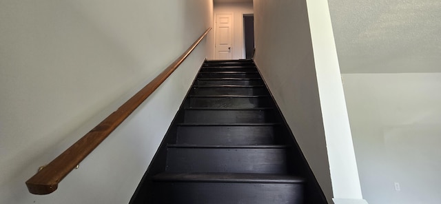 stairs featuring a textured ceiling