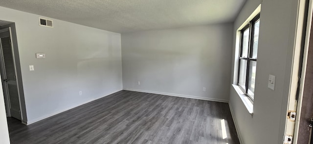 spare room with dark hardwood / wood-style floors and a textured ceiling